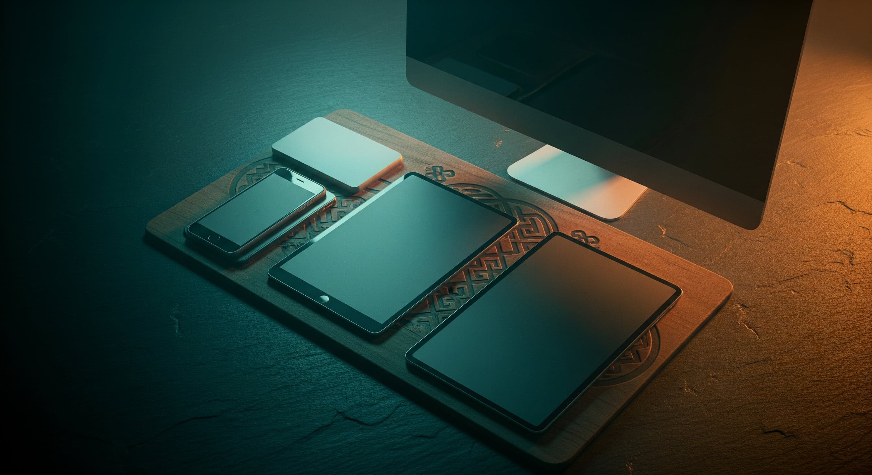 Overhead flat-lay of multiple devices on a dark surface with faint Mongolian knot pattern.